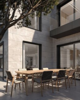 Outdoor dining terrace shaded by mature trees beside the villa