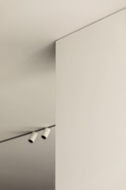 Біла колона та стельові трекові світильники у вітальні / White column and ceiling track lights in the living room