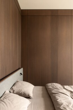 Спальня з ліжком та стіною вбудованих дерев&rsquo;яних шаф / Bedroom with a bed and a wall of built-in wood wardrobes
