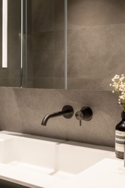 Настінний змішувач над білою раковиною, крупний план / Wall-mounted faucet above a white basin, close-up