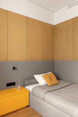 Дитяча спальня із сірим м&rsquo;яким ліжком і жовтою тумбою / Child&rsquo;s bedroom with a gray upholstered bed and yellow bedside cabinet